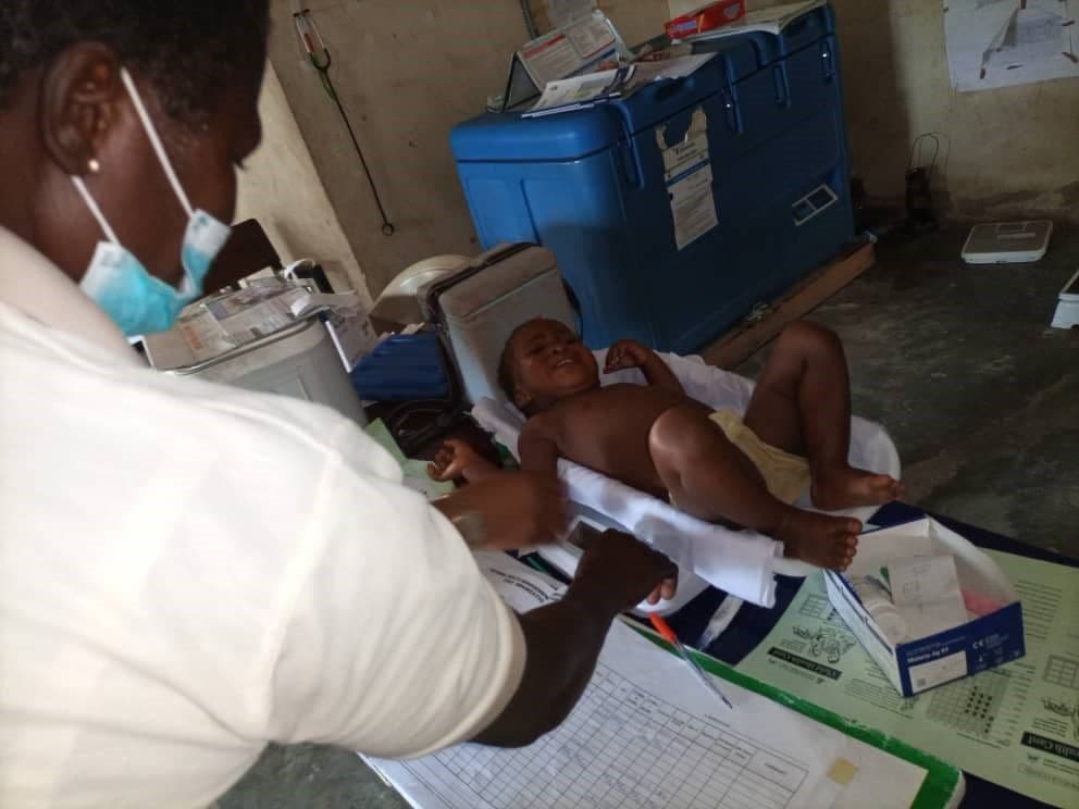 Trainee weighing a nine-month-old baby at Okaria MDGs PHC