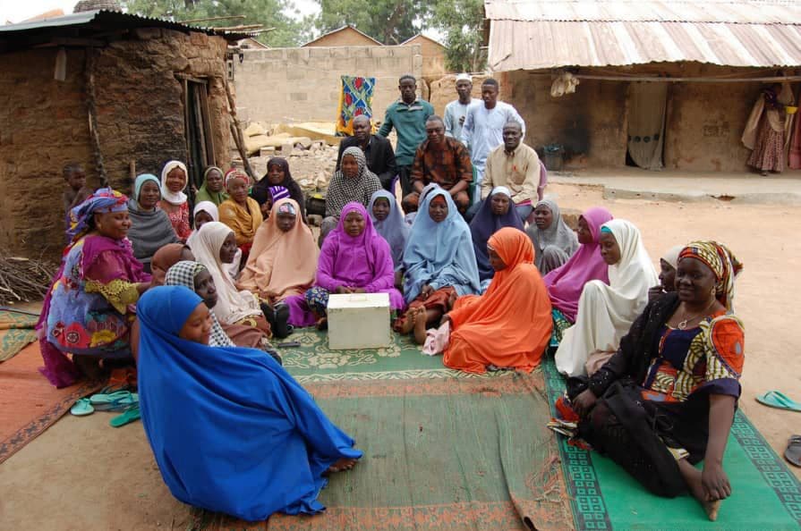 Village savings group members seated on mats during a meeting
