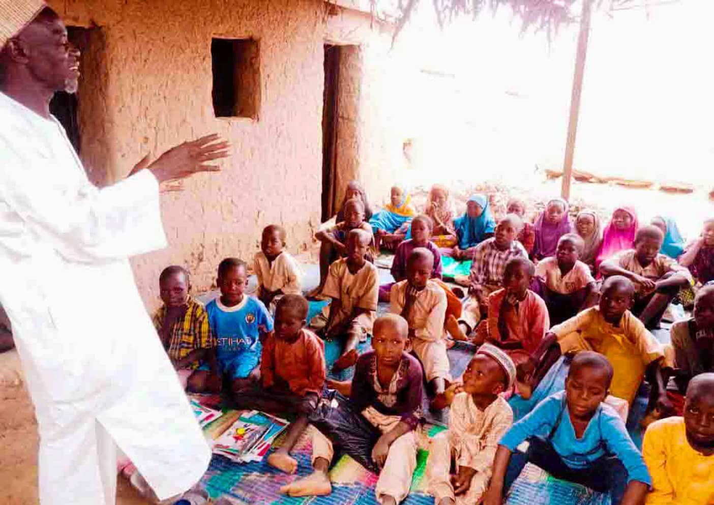 Facilitator teaching a large group of children at a community learning centre