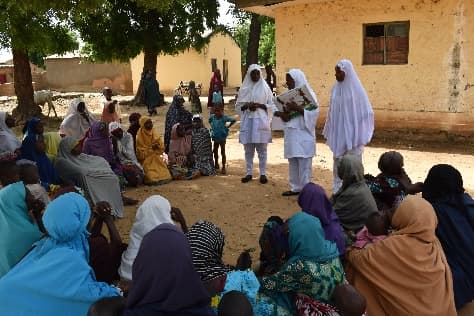 LHI health workers leading a maternal and child health session with mothers under a tree