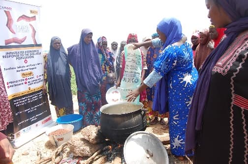 Women gathered round a cooking pot at an LHI nutrition awareness session