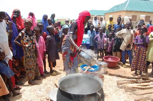 Mothers and children watching a community nutrition cooking demonstration