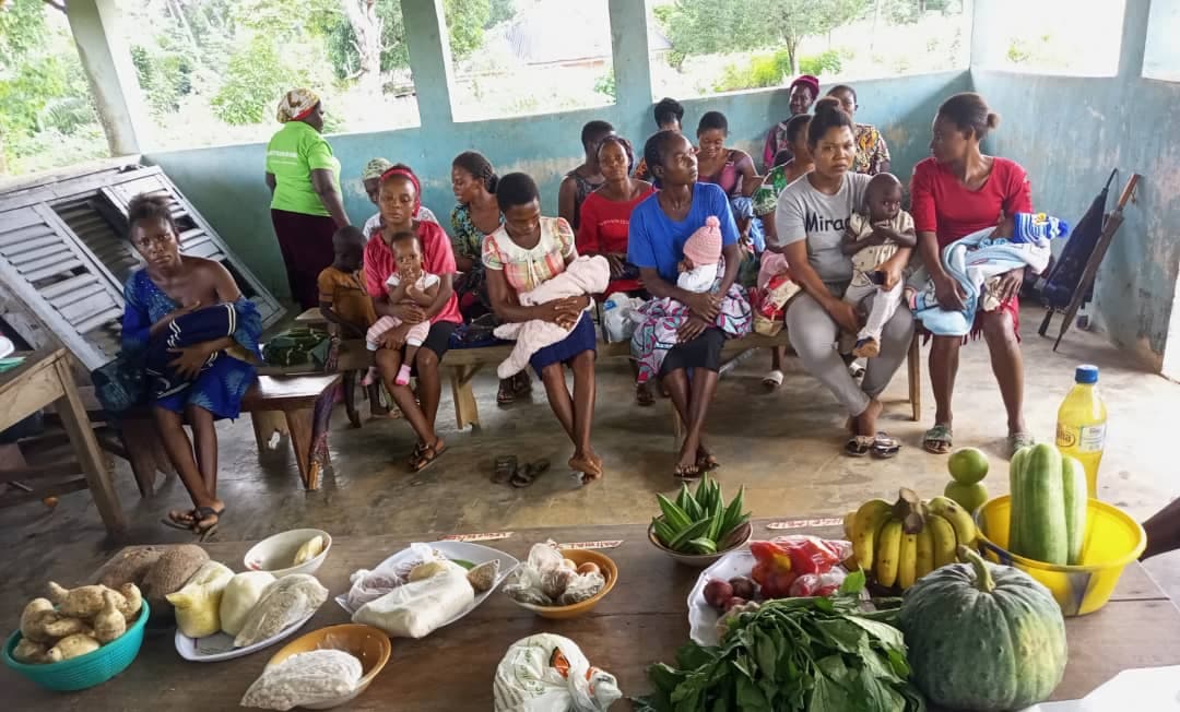 Mothers with their babies at a food demonstration with vegetables, grains and fruit