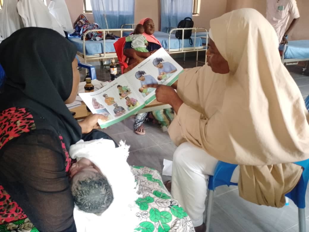 Health worker using a counselling card with mothers during an immunisation session